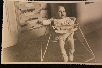 Une photo d'antan d'un tout petit dans son trotteur en ferraille